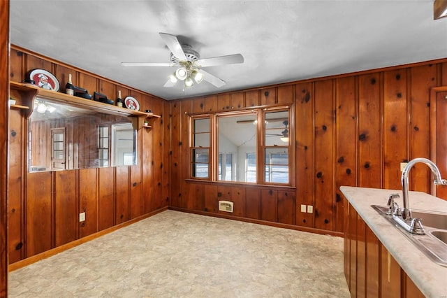 unfurnished dining area with sink, wood walls, and ceiling fan