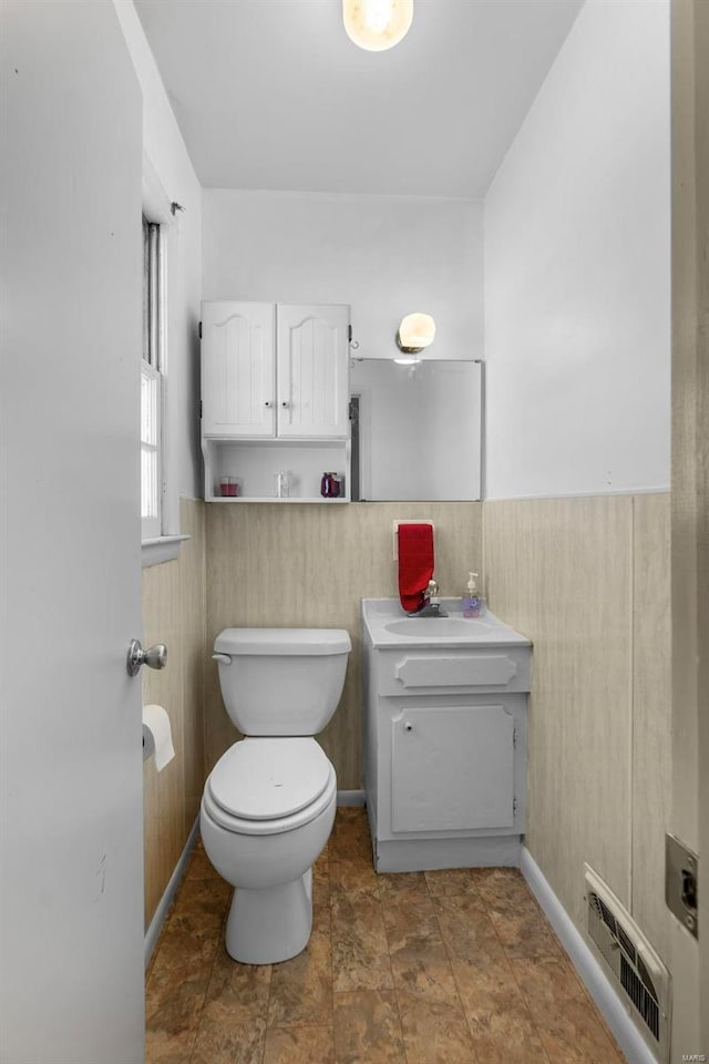 bathroom with sink, toilet, and wood walls