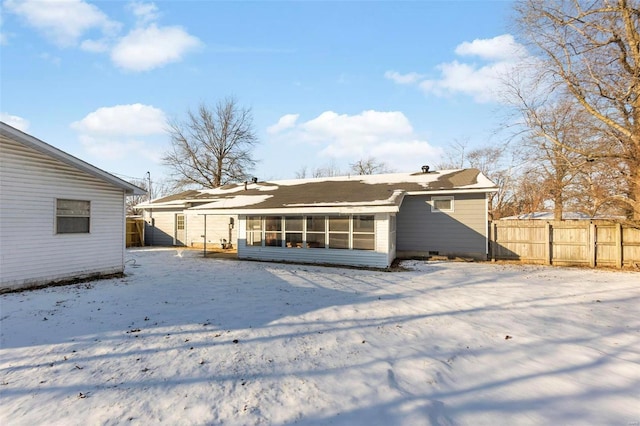 snow covered rear of property featuring a sunroom