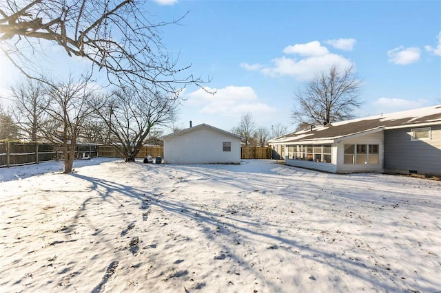 snow covered rear of property with a sunroom