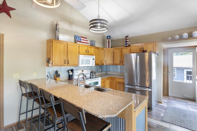 kitchen featuring pendant lighting, white appliances, a breakfast bar, kitchen peninsula, and a chandelier