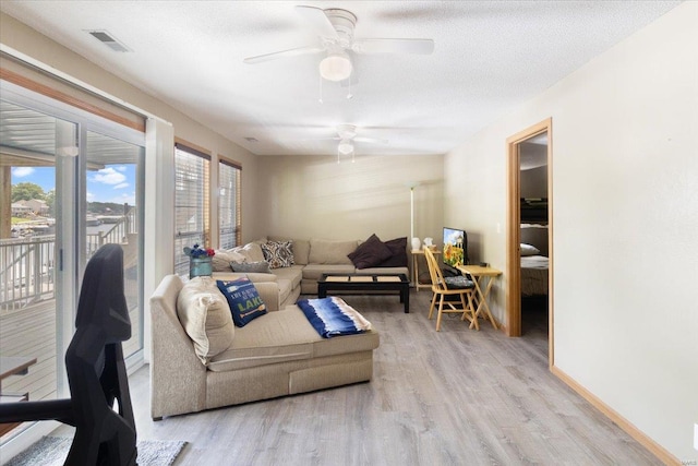 living room with ceiling fan, light hardwood / wood-style floors, and a textured ceiling