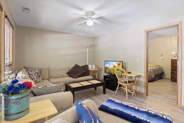 living room featuring a textured ceiling, light hardwood / wood-style flooring, and ceiling fan