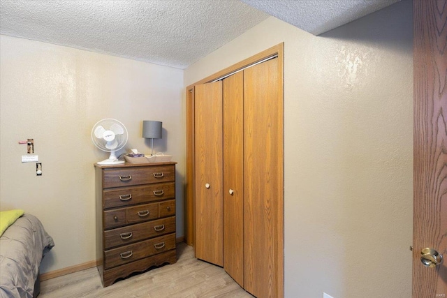 bedroom with light hardwood / wood-style flooring, a closet, and a textured ceiling