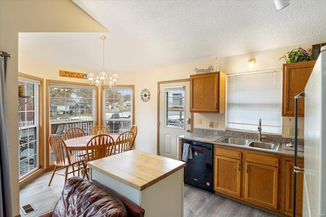 kitchen with pendant lighting, sink, black dishwasher, wood-type flooring, and a chandelier