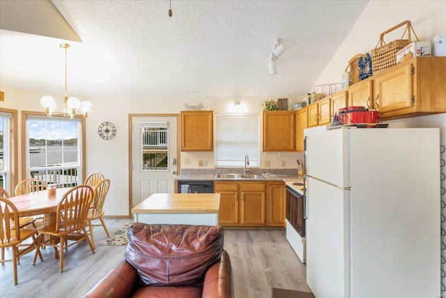 kitchen featuring sink, decorative light fixtures, a textured ceiling, white appliances, and light hardwood / wood-style floors