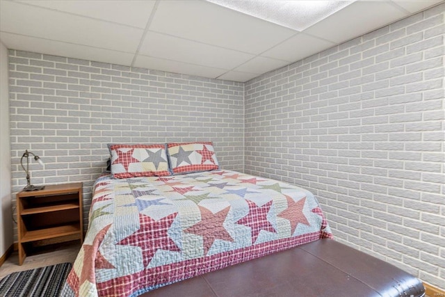 bedroom with brick wall and a drop ceiling