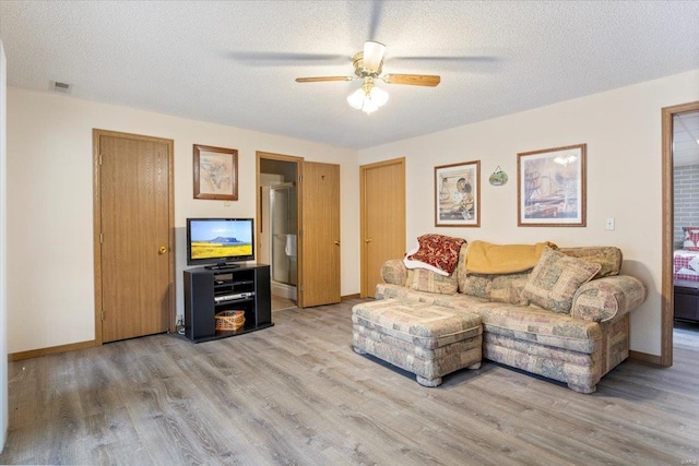 living room with ceiling fan, a textured ceiling, and light hardwood / wood-style flooring