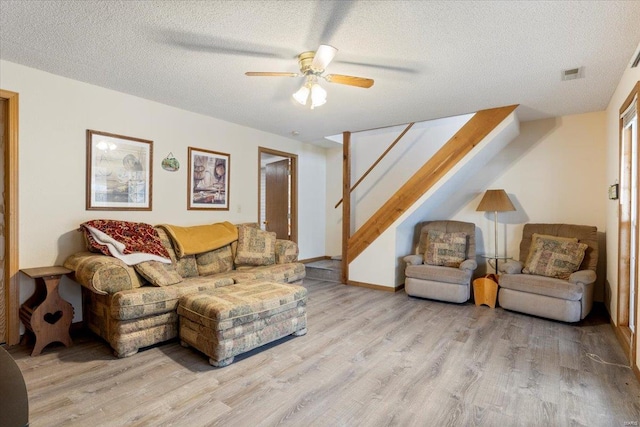 living room with ceiling fan, a textured ceiling, and light hardwood / wood-style floors