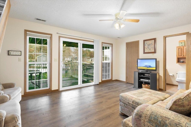 living room featuring wood-type flooring, ceiling fan, and a textured ceiling