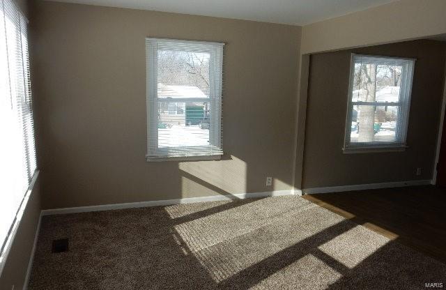 unfurnished room featuring dark carpet and a healthy amount of sunlight