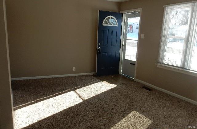 foyer featuring dark carpet, visible vents, and baseboards