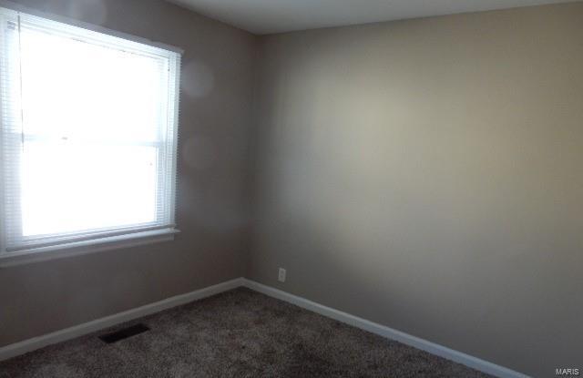 unfurnished room featuring carpet, visible vents, and baseboards