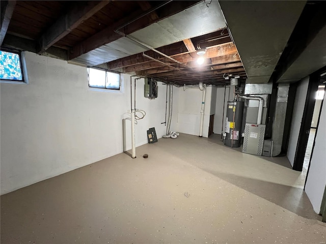 basement featuring gas water heater, heating unit, and electric panel