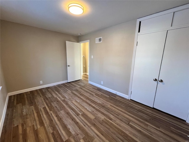 unfurnished bedroom with dark wood-type flooring and a closet