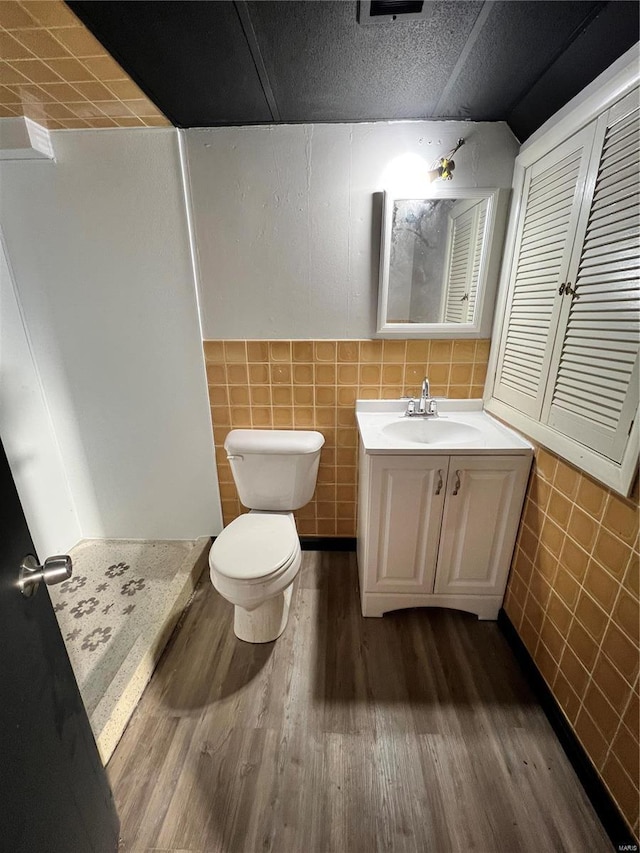 bathroom featuring tile walls, vanity, wood-type flooring, and toilet