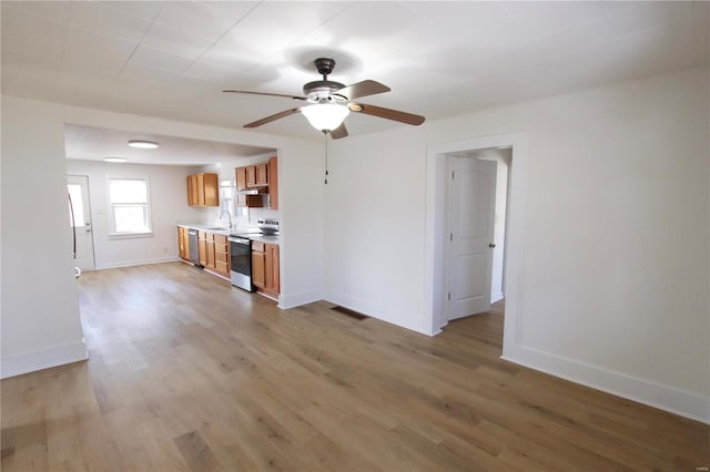 unfurnished living room with sink, light wood-type flooring, and ceiling fan