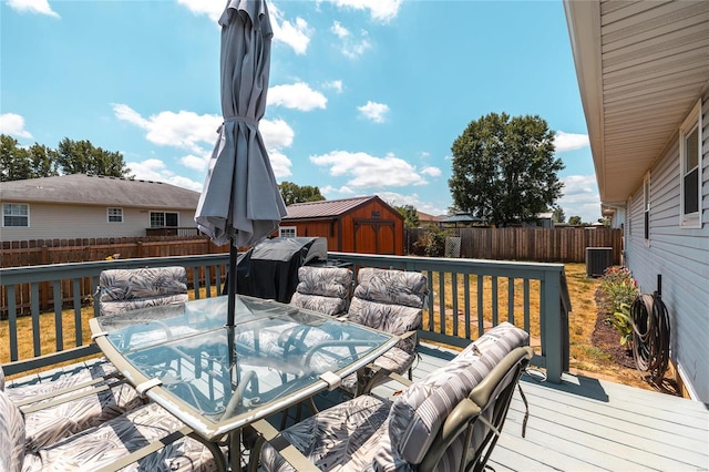 wooden deck with central AC unit, area for grilling, and a storage unit