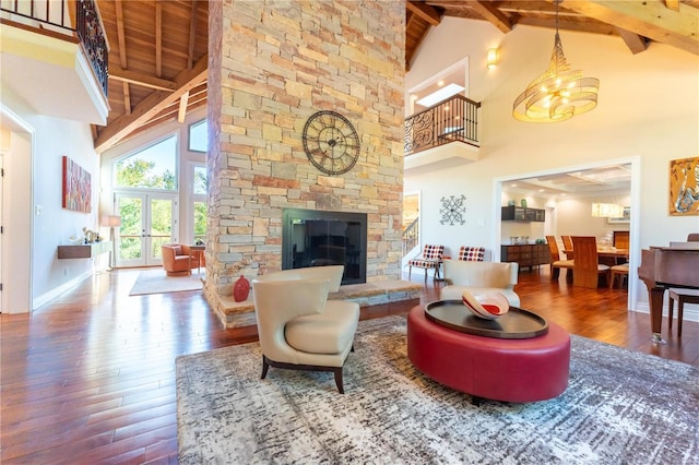 living room with a stone fireplace, hardwood / wood-style floors, beam ceiling, and french doors