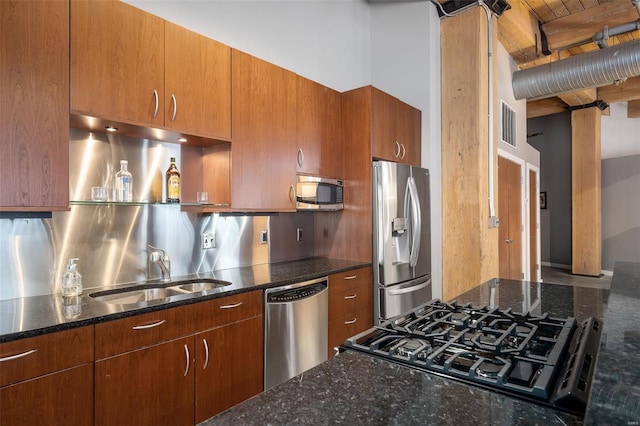 kitchen with sink, stainless steel appliances, and dark stone counters