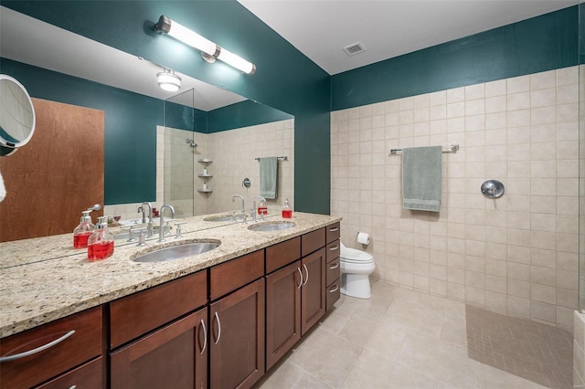 bathroom featuring tiled shower, toilet, tile patterned flooring, and vanity