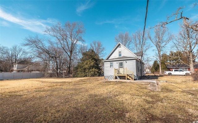 back of house featuring fence and a lawn