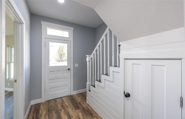 foyer entrance featuring dark wood-style flooring, vaulted ceiling, stairway, and baseboards