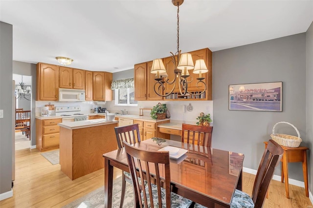 dining space featuring sink, light hardwood / wood-style flooring, and a notable chandelier