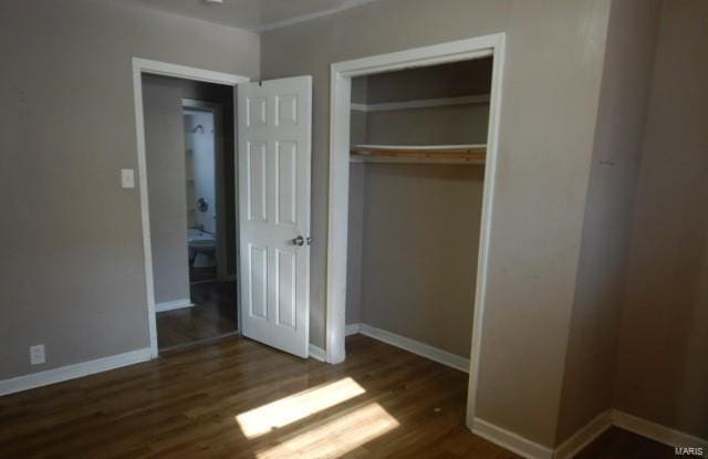 unfurnished bedroom with dark hardwood / wood-style floors and a closet