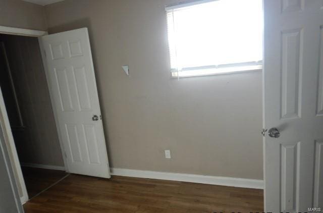 unfurnished bedroom with dark hardwood / wood-style flooring and a closet