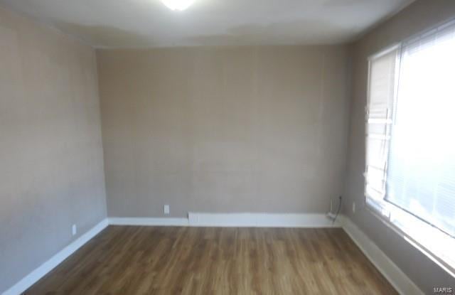 spare room with baseboards and wood finished floors