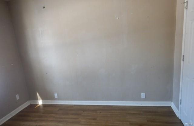 empty room featuring baseboards and dark wood-type flooring