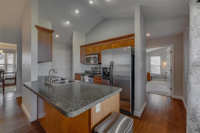 kitchen with appliances with stainless steel finishes, a kitchen bar, sink, kitchen peninsula, and vaulted ceiling