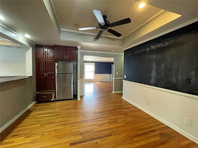 kitchen featuring ceiling fan, light hardwood / wood-style floors, stainless steel fridge, and a tray ceiling