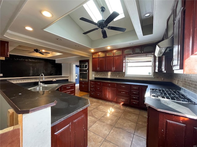 kitchen featuring a spacious island, a raised ceiling, sink, tasteful backsplash, and ventilation hood