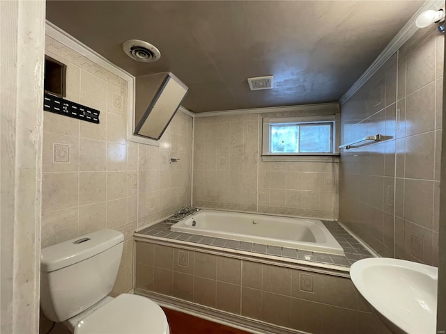 bathroom with crown molding, toilet, tiled tub, and tile walls