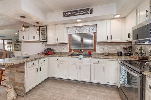 kitchen featuring stainless steel appliances, white cabinetry, pendant lighting, and kitchen peninsula