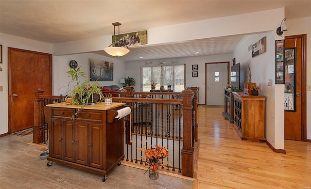 kitchen with decorative light fixtures, a center island, and light wood-type flooring