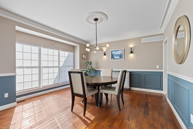 dining space featuring an inviting chandelier, crown molding, and wood-type flooring