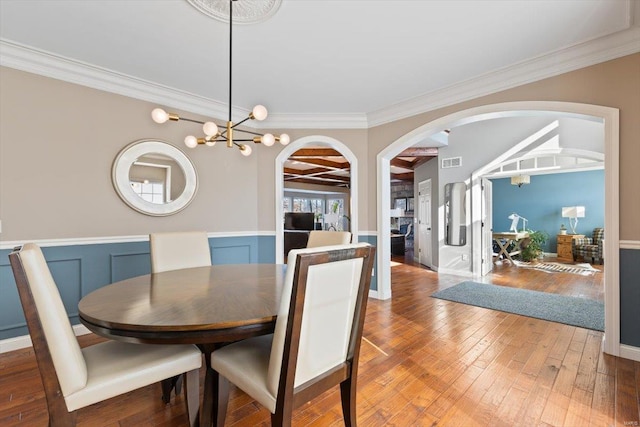 dining space with crown molding, a chandelier, and hardwood / wood-style floors