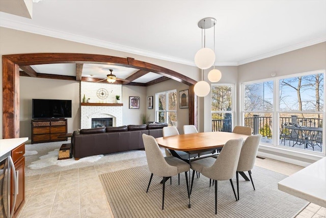 dining area with ceiling fan, crown molding, a fireplace, and beam ceiling