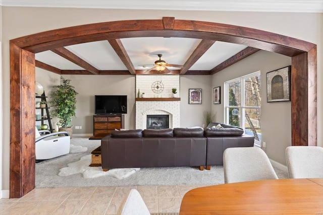 living room featuring light carpet, ceiling fan, a fireplace, and beamed ceiling