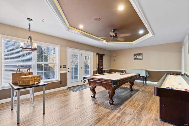 rec room featuring a tray ceiling, ornamental molding, ceiling fan, and light wood-type flooring