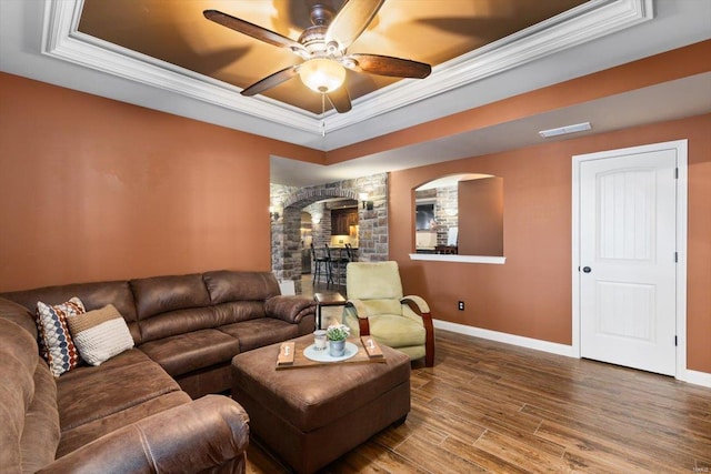 living room featuring crown molding, wood-type flooring, ceiling fan, and a tray ceiling