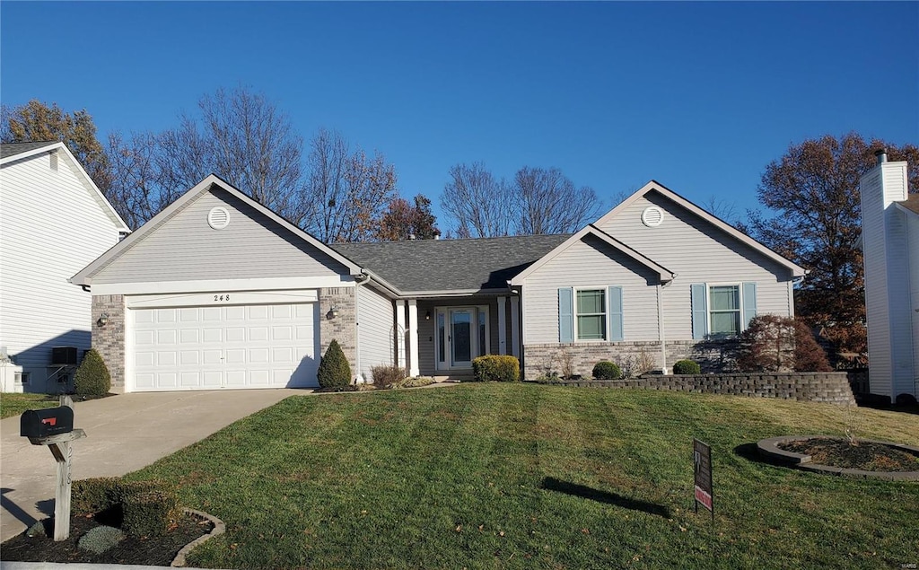 ranch-style home featuring a garage and a front lawn