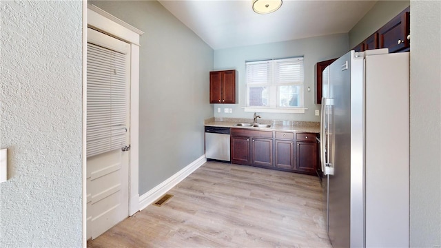 kitchen featuring stainless steel appliances, sink, and light hardwood / wood-style flooring