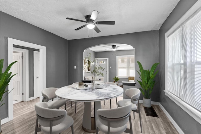 dining space with ceiling fan, a textured ceiling, and light hardwood / wood-style flooring