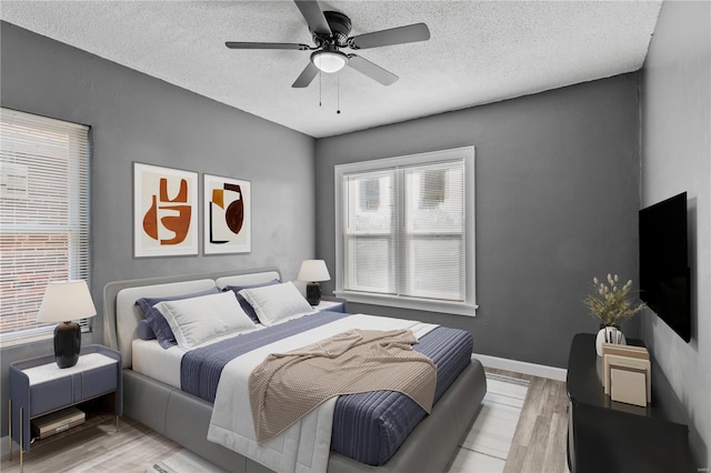 bedroom with ceiling fan, light hardwood / wood-style floors, and a textured ceiling