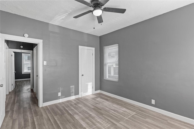 spare room featuring hardwood / wood-style flooring, a textured ceiling, a wealth of natural light, and ceiling fan