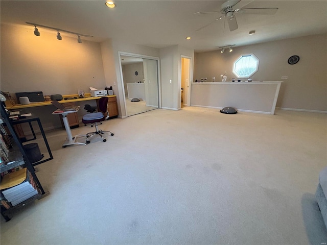 carpeted office space with ceiling fan and track lighting